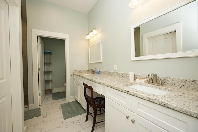 bathroom with a sink, toilet, double vanity, and marble finish floor