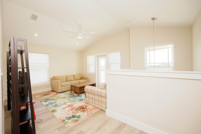 living room featuring visible vents, wood finished floors, baseboards, a ceiling fan, and vaulted ceiling