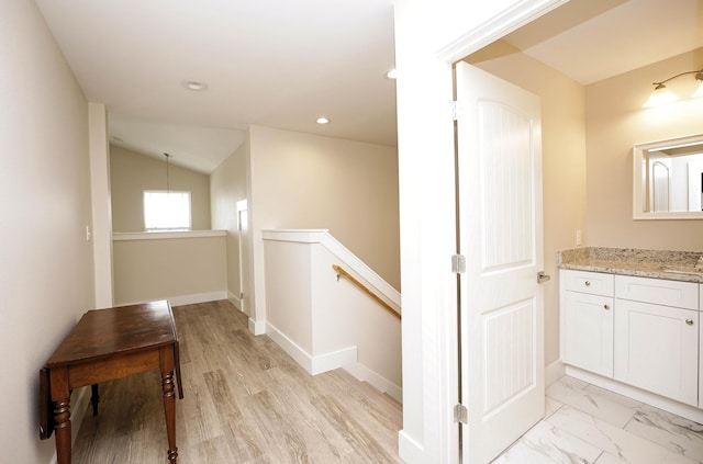 corridor with lofted ceiling, baseboards, recessed lighting, a sink, and an upstairs landing