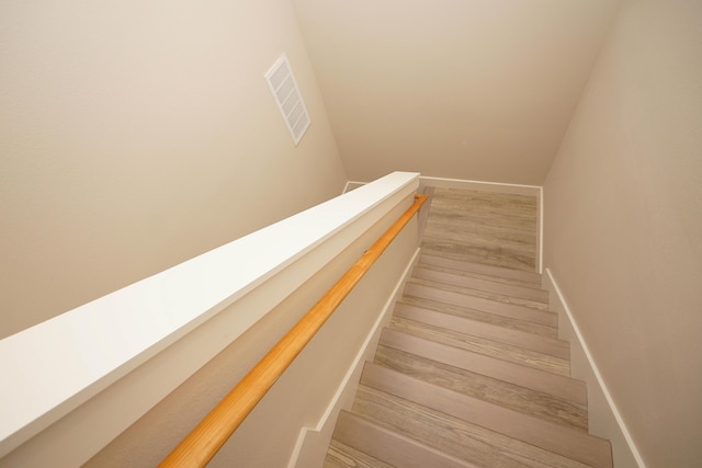 stairs featuring baseboards, wood finished floors, and visible vents