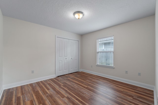 2690 Hartman Ct, Navarre, FL 32566 - unfurnished bedroom with baseboards, a closet, a textured ceiling, and dark wood-type flooring