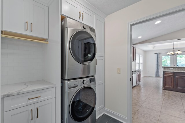 2690 Hartman Ct, Navarre, FL 32566 - washroom featuring cabinet space, stacked washer / dryer, a chandelier, light tile patterned floors, and baseboards