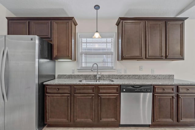 2690 Hartman Ct, Navarre, FL 32566 - kitchen with dark brown cabinetry, stainless steel appliances, light stone counters, and a sink