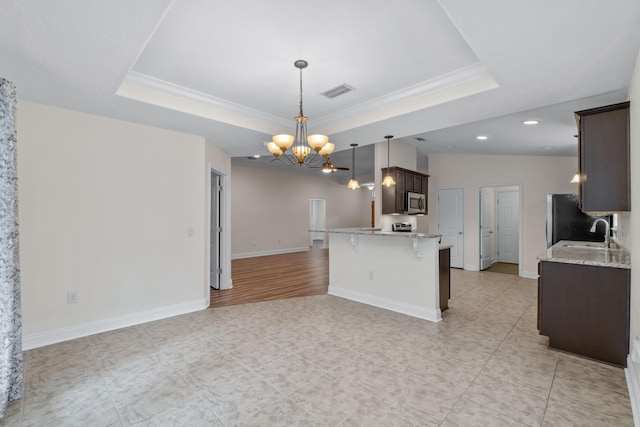 2690 Hartman Ct, Navarre, FL 32566 - kitchen featuring stainless steel microwave, a raised ceiling, open floor plan, and a notable chandelier