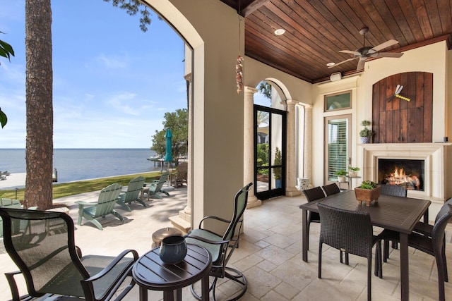 3002 Bay Villas Dr, Miramar Beach, FL 32550 - view of patio / terrace featuring a water view, ceiling fan, a warm lit fireplace, and outdoor dining area