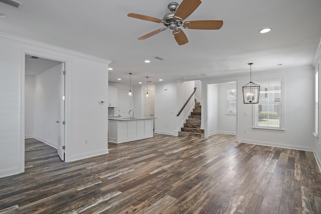 unfurnished living room featuring stairs, baseboards, dark wood-style floors, recessed lighting, and a sink