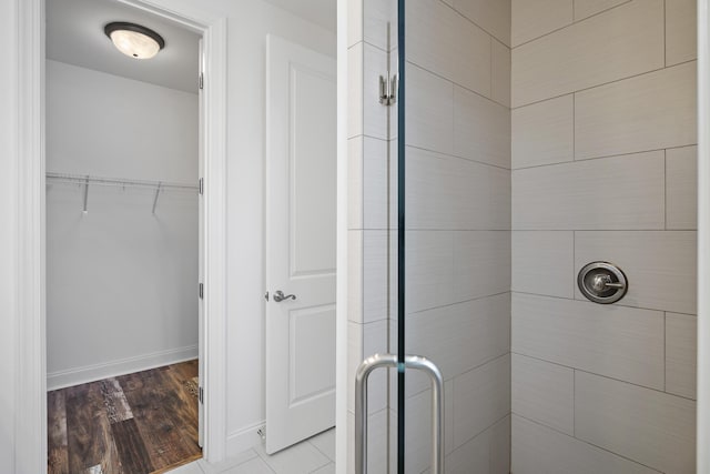 bathroom featuring baseboards, a shower stall, and wood finished floors