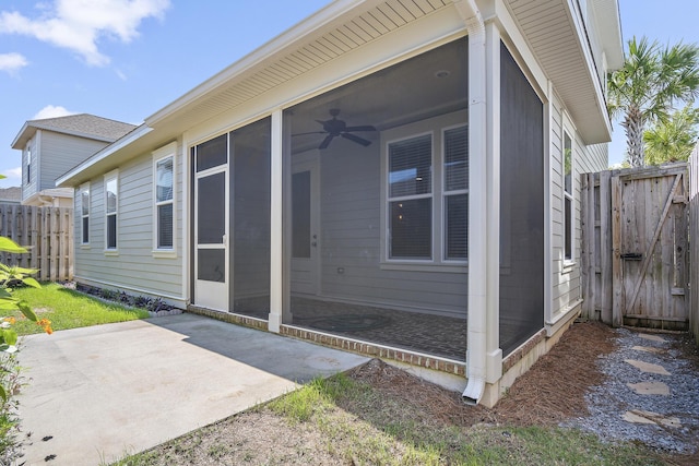 rear view of property featuring fence, a gate, a sunroom, and a patio area