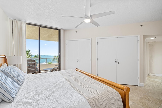 100 Gulf Shore Dr Unit 202, Destin, FL 32541 - bedroom featuring two closets, access to outside, a textured ceiling, a water view, and a ceiling fan
