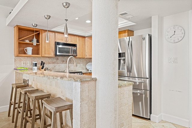 100 Gulf Shore Dr Unit 202, Destin, FL 32541 - kitchen with light stone countertops, appliances with stainless steel finishes, a peninsula, baseboards, and backsplash