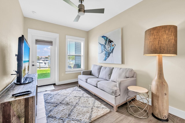 living area featuring baseboards, a ceiling fan, and wood finished floors