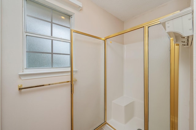 full bathroom featuring a textured ceiling and a shower stall