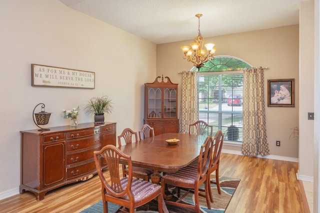 dining area with baseboards, an inviting chandelier, and light wood finished floors