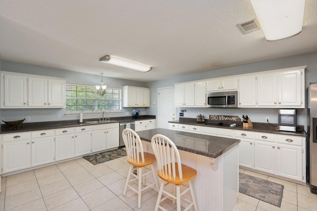 kitchen with light tile patterned floors, stainless steel appliances, white cabinetry, and visible vents