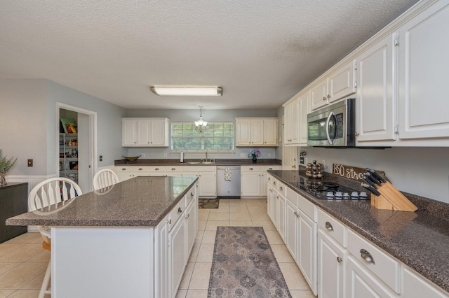 kitchen featuring a kitchen island, a kitchen bar, wainscoting, stainless steel appliances, and light tile patterned flooring