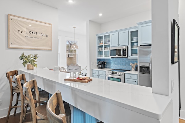 97 Sarasota St, Miramar Beach, FL 32550 - kitchen with a peninsula, glass insert cabinets, a kitchen breakfast bar, appliances with stainless steel finishes, and backsplash