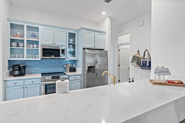 97 Sarasota St, Miramar Beach, FL 32550 - kitchen with decorative backsplash, open shelves, light stone countertops, glass insert cabinets, and appliances with stainless steel finishes