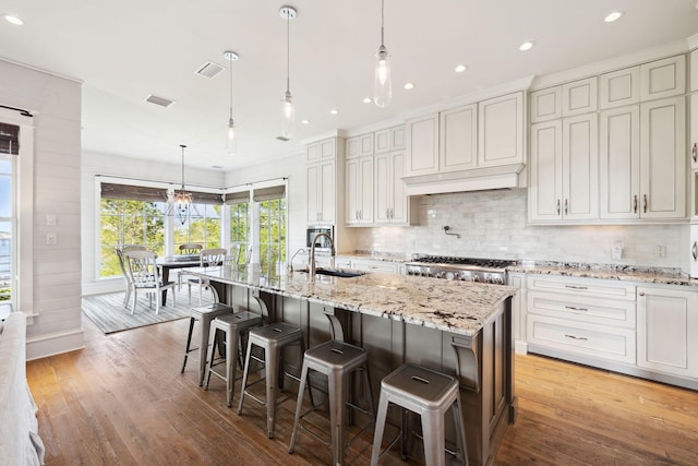 68 Creek Bridge Way, Watersound, FL 32461 - kitchen featuring a sink, light wood finished floors, an island with sink, and tasteful backsplash