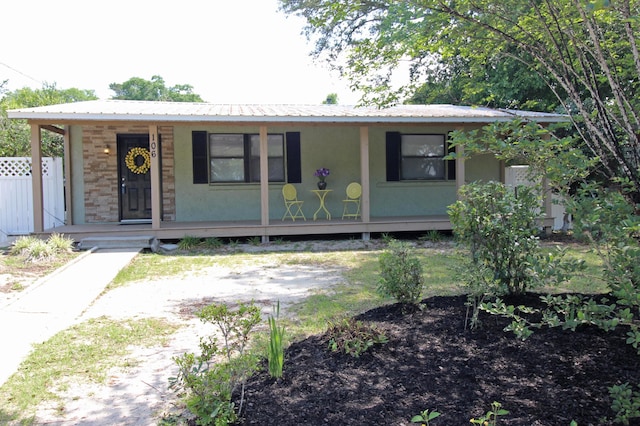 view of front of house featuring metal roof, a porch, and stucco siding
