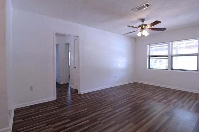 unfurnished room featuring baseboards, a ceiling fan, visible vents, and dark wood finished floors