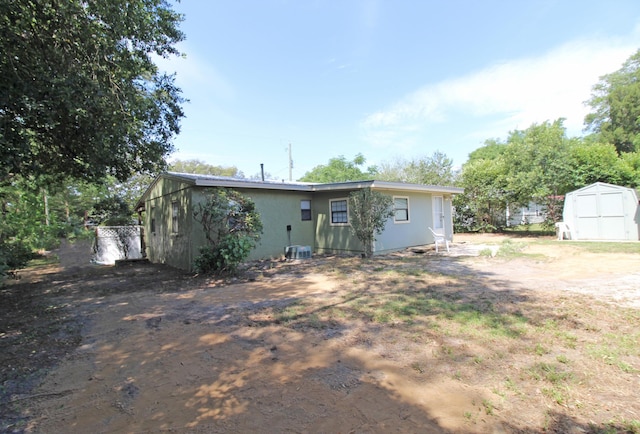 back of house featuring a storage shed, an outbuilding, and central AC