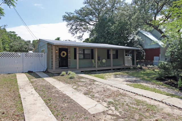 bungalow with covered porch, fence, and metal roof
