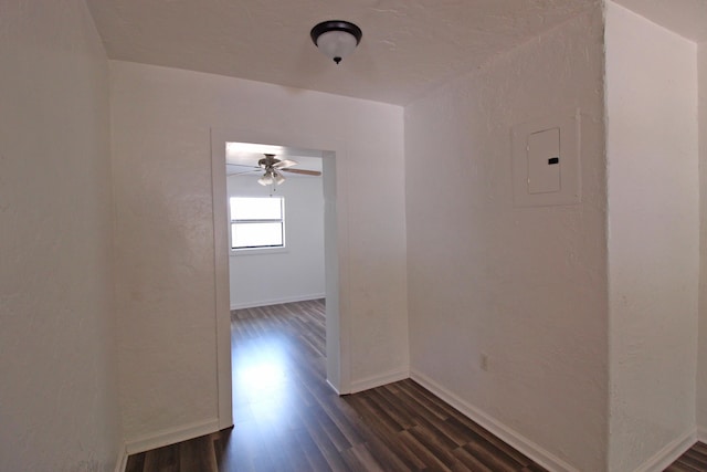 empty room with electric panel, baseboards, ceiling fan, and dark wood-style floors