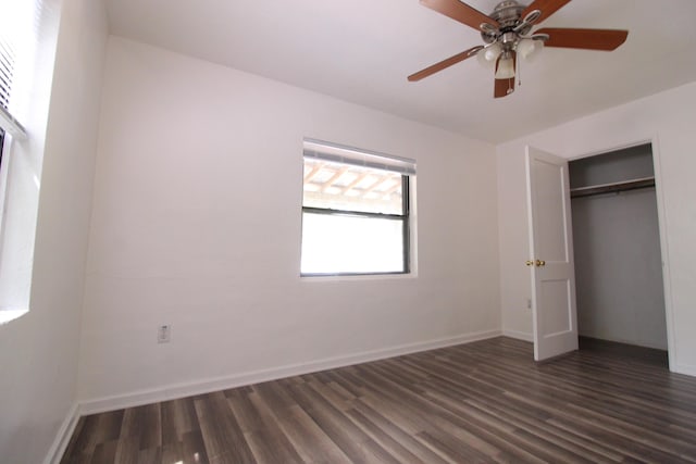 unfurnished bedroom featuring ceiling fan, baseboards, dark wood-style floors, and a closet