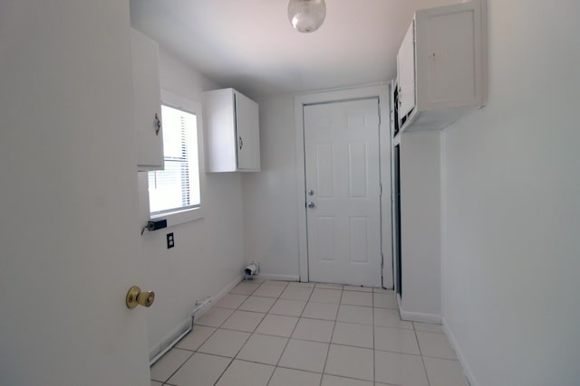 laundry area featuring cabinet space, baseboards, hookup for a gas dryer, and light tile patterned floors