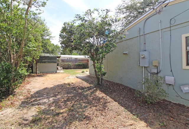 view of yard with an outdoor structure, fence, and a shed