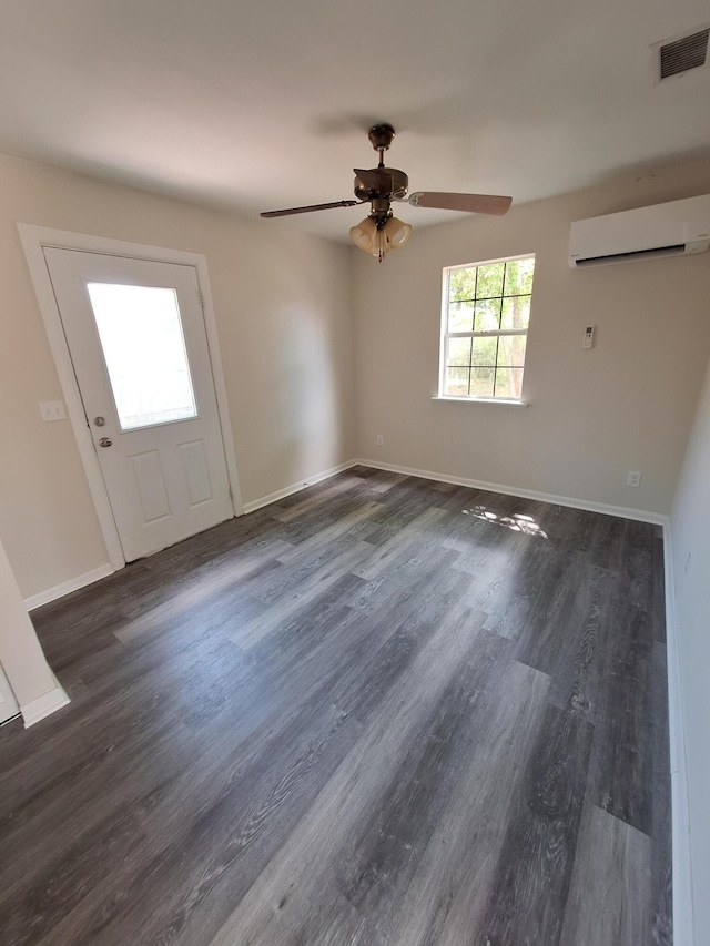 empty room featuring a wall mounted air conditioner, a ceiling fan, wood finished floors, and visible vents