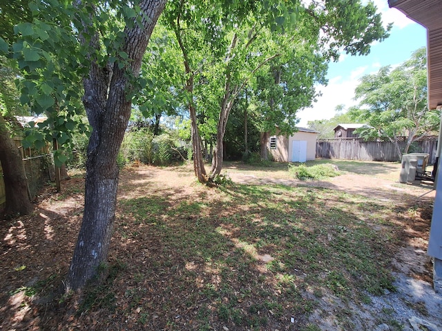 view of yard with fence, an outdoor structure, and a shed