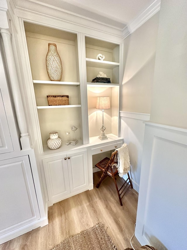 detailed view of wood finished floors, wainscoting, and crown molding