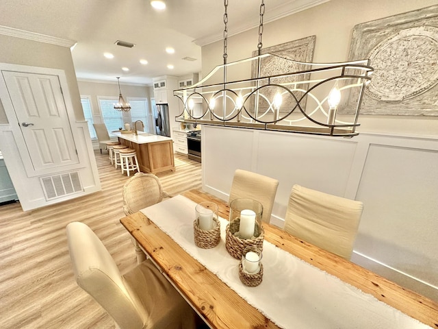 dining space featuring crown molding, a chandelier, light wood finished floors, and recessed lighting