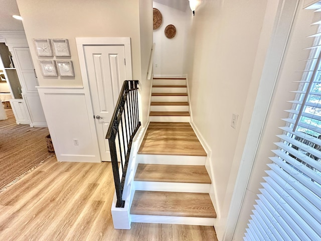 staircase featuring wood finished floors and baseboards