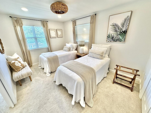 bedroom with light colored carpet, multiple windows, and baseboards