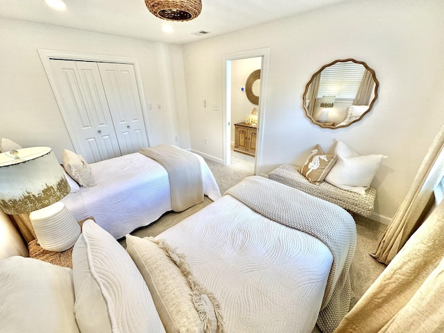 bedroom featuring light colored carpet, baseboards, a closet, and connected bathroom