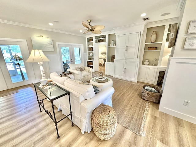 living area with ceiling fan, french doors, light wood-style floors, crown molding, and built in features