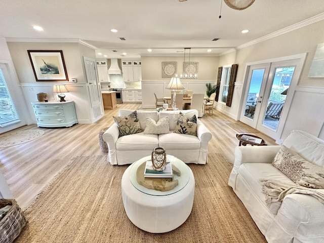 living area with light wood-type flooring, a decorative wall, ornamental molding, wainscoting, and recessed lighting