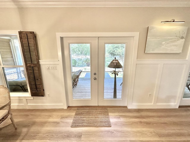 doorway featuring crown molding, french doors, light wood-type flooring, and baseboards