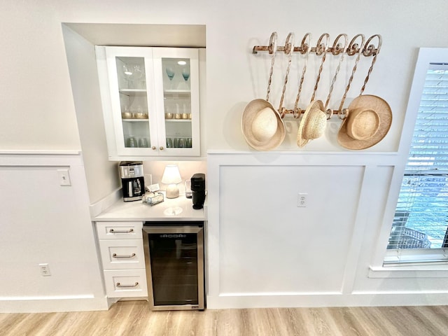 indoor dry bar with wine cooler and light wood-style floors