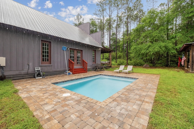 outdoor pool with a lawn, a patio area, french doors, and entry steps