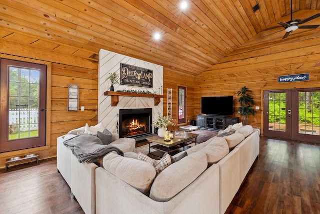 living area with dark wood-type flooring, lofted ceiling, wooden walls, and a fireplace