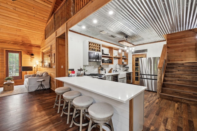 kitchen with open shelves, appliances with stainless steel finishes, light countertops, a peninsula, and dark wood-style floors