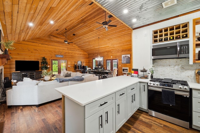 kitchen featuring wooden walls, ceiling fan, appliances with stainless steel finishes, a peninsula, and lofted ceiling