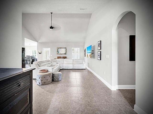 214 Whispering Lake Dr, Santa Rosa Beach, FL 32459 - living area featuring baseboards, arched walkways, dark tile patterned floors, high vaulted ceiling, and a textured ceiling