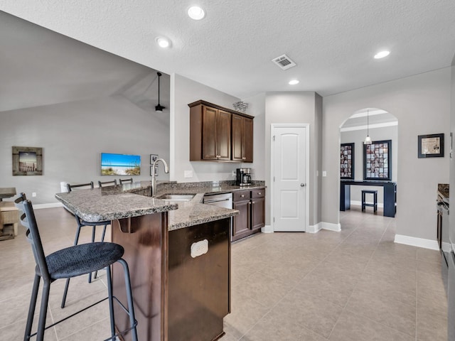 214 Whispering Lake Dr, Santa Rosa Beach, FL 32459 - kitchen featuring dark stone countertops, a sink, arched walkways, a breakfast bar, and a peninsula