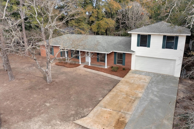 split level home featuring roof with shingles, a porch, driveway, and a garage
