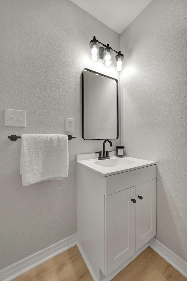 bathroom with vanity, baseboards, and wood finished floors
