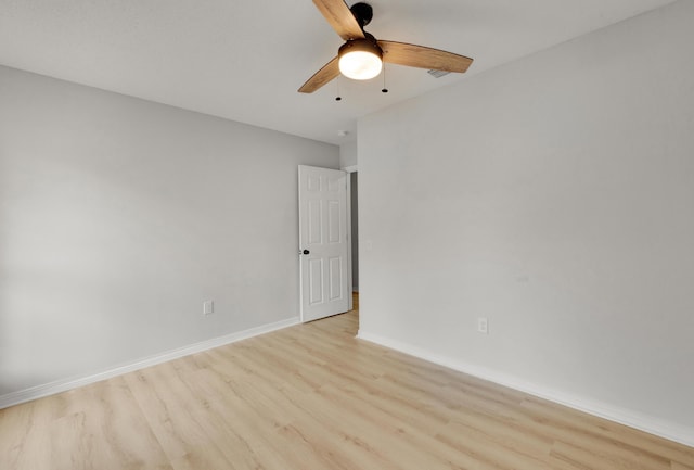 spare room featuring baseboards, a ceiling fan, and light wood-style flooring